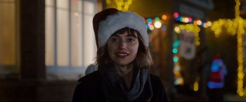 Movie still from “Black Christmas” (2019), directed by Sophia Takal – A woman wearing a santa clause hat in front of a window; Close Up shot, Over the shoulder angle