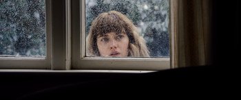 Movie still from “Black Christmas” (2019), directed by Sophia Takal – A woman looking out of a window through a window; Close Up shot, Low angle