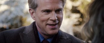 Movie still from “Black Christmas” (2019), directed by Sophia Takal – An older man wearing a suit and tie; Close Up shot, Over the shoulder angle