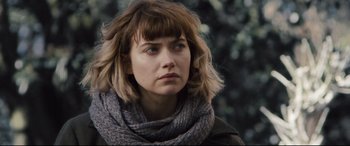 Movie still from “Black Christmas” (2019), directed by Sophia Takal – A person wearing a scarf with trees in the background; Close Up shot, Over the shoulder angle