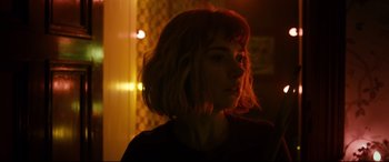 Movie still from “Black Christmas” (2019), directed by Sophia Takal – A woman with red hair is standing in a room; Close Up shot, Over the shoulder angle