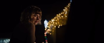 Movie still from “Black Christmas” (2019), directed by Sophia Takal – A woman standing in front of a string of lights; Close Up shot, Low angle