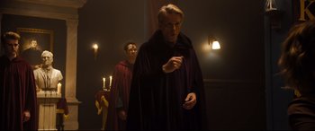 Movie still from “Black Christmas” (2019), directed by Sophia Takal – A man in a purple robe standing next to another man in a red robe; Medium shot, Over the shoulder angle