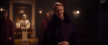 Movie still from “Black Christmas” (2019), directed by Sophia Takal – A man in a purple robe standing next to another man in a red robe; Medium shot, Over the shoulder angle