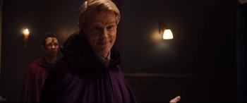 Movie still from “Black Christmas” (2019), directed by Sophia Takal – A man wearing a purple robe and a red tie; Medium shot, Over the shoulder angle