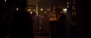 Movie still from “Black Christmas” (2019), directed by Sophia Takal – A group of people dressed in robes and hoods in a dark room; Wide shot, High angle