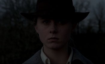 Movie still from “Black Moon” (1975), directed by Louis Malle – A woman wearing a hat in the dark; Close Up shot, Low angle