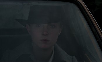 Movie still from “Black Moon” (1975), directed by Louis Malle – A man in a hat sitting in the back seat of a car; Close Up shot, Low angle