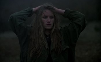 Movie still from “Black Moon” (1975), directed by Louis Malle – A woman with long brown hair holding her hands in her hair; Close Up shot, High angle