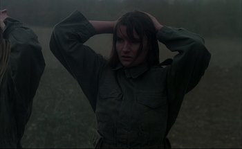 Movie still from “Black Moon” (1975), directed by Louis Malle – A woman is standing in a field with her hands behind her head; Close Up shot, Low angle