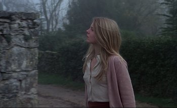 Movie still from “Black Moon” (1975), directed by Louis Malle – A young woman is walking down the street; Medium shot, Low angle