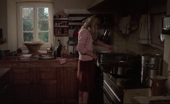 Movie still from “Black Moon” (1975), directed by Louis Malle – A woman standing in front of an oven in a kitchen; Wide shot, High angle