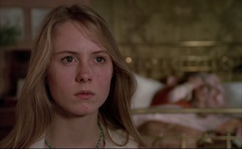 Movie still from “Black Moon” (1975), directed by Louis Malle – A woman with long blonde hair wearing a white shirt; Close Up shot, Low angle
