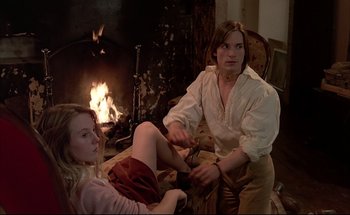 Movie still from “Black Moon” (1975), directed by Louis Malle – A man and a woman sitting in front of a fireplace; Medium shot, High angle