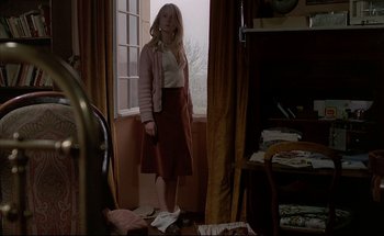 Movie still from “Black Moon” (1975), directed by Louis Malle – A woman standing in front of a window in a room; Wide shot, Low angle