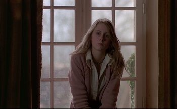 Movie still from “Black Moon” (1975), directed by Louis Malle – A woman sitting in front of a large window; Close Up shot, Low angle
