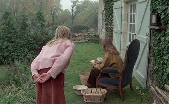 Movie still from “Black Moon” (1975), directed by Louis Malle – Two women sitting on a lawn in front of a house; Wide shot, High angle