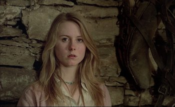 Movie still from “Black Moon” (1975), directed by Louis Malle – A woman with long blonde hair wearing a white shirt; Close Up shot, Low angle