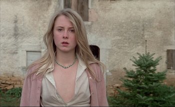 Movie still from “Black Moon” (1975), directed by Louis Malle – A young blonde woman wearing a white shirt and a pink jacket; Close Up shot, Low angle