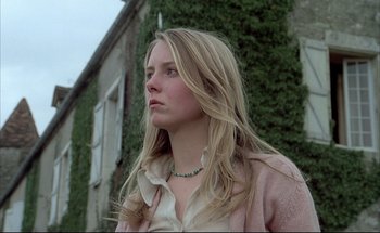 Movie still from “Black Moon” (1975), directed by Louis Malle – A woman with long blonde hair wearing a white shirt; Close Up shot, Low angle