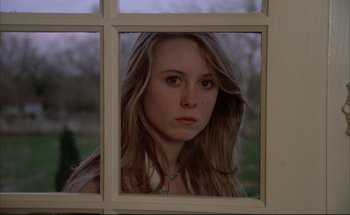 Movie still from “Black Moon” (1975), directed by Louis Malle – A young woman looking out of a window at dusk; Close Up shot, Low angle