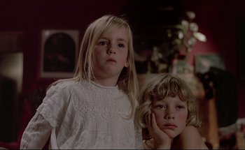 Movie still from “Black Moon” (1975), directed by Louis Malle – Two little girls sitting next to each other in a living room; Close Up shot, Low angle