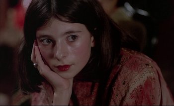 Movie still from “Black Moon” (1975), directed by Louis Malle – A young girl is sitting with her head resting on her hand; Close Up shot, High angle