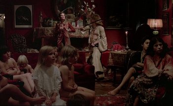 Movie still from “Black Moon” (1975), directed by Louis Malle – A group of people sitting in a living room; Wide shot, High angle