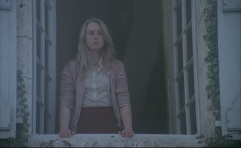 Movie still from “Black Moon” (1975), directed by Louis Malle – A woman standing in front of an open window; Medium shot, Low angle