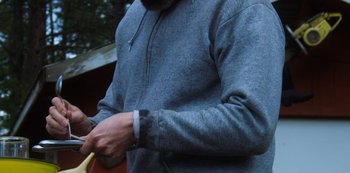 Movie still from “Ted K” (2021), directed by Tony Stone – A man in a gray hoodie holding a yellow object; Medium shot, Low angle