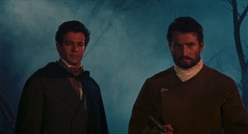 Movie still from “Black Sabbath” (1963), directed by Mario Bava – Two men standing next to each other in front of a blue background; Medium shot, Low angle