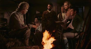 Movie still from “Black Sabbath” (1963), directed by Mario Bava – A group of people gathered around a fire; Medium shot, Over the shoulder angle
