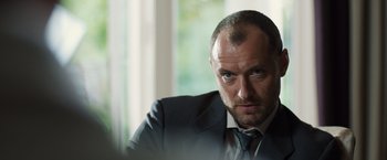 Movie still from “Black Sea” (2014), directed by Kevin Macdonald – A person wearing a suit and tie; Close Up shot, Low angle