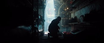Movie still from “Black Sea” (2014), directed by Kevin Macdonald – A man kneeling down in the middle of an industrial setting; Wide shot, Low angle