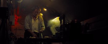 Movie still from “Black Sea” (2014), directed by Kevin Macdonald – A man standing at a table in front of a stove; Medium shot, Low angle