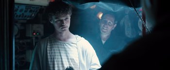 Movie still from “Black Sea” (2014), directed by Kevin Macdonald – A man standing next to another man under a umbrella; Close Up shot, Over the shoulder angle