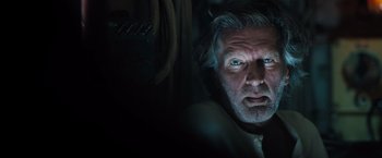 Movie still from “Black Sea” (2014), directed by Kevin Macdonald – An older man stares into the camera with blue light coming from his eyes; Close Up shot, Low angle