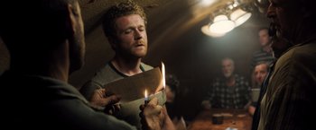 Movie still from “Black Sea” (2014), directed by Kevin Macdonald – A man is holding a lit match in his hand; Medium shot, Low angle