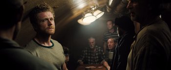 Movie still from “Black Sea” (2014), directed by Kevin Macdonald – A group of men sitting around a table; Medium shot, Over the shoulder angle