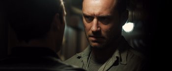 Movie still from “Black Sea” (2014), directed by Kevin Macdonald – A person looking at the camera; Close Up shot, Over the shoulder angle