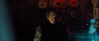 Movie still from “Black Sea” (2014), directed by Kevin Macdonald – A man in a dark room looking at the camera; Medium shot, Low angle