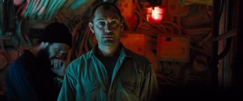 Movie still from “Black Sea” (2014), directed by Kevin Macdonald – A man standing in front of a wall with lights; Close Up shot, Low angle