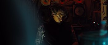 Movie still from “Black Sea” (2014), directed by Kevin Macdonald – A man in a dark room looking at the camera; Medium shot, Low angle