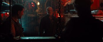 Movie still from “Black Sea” (2014), directed by Kevin Macdonald – An older man standing in front of a mirror in a dark room; Medium shot, Over the shoulder angle