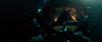 Movie still from “Black Sea” (2014), directed by Kevin Macdonald – A man in a scuba diving suit in the dark; Close Up shot, Overhead angle