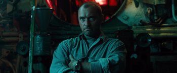 Movie still from “Black Sea” (2014), directed by Kevin Macdonald – A man with a beard is standing with his arms crossed; Close Up shot, Low angle