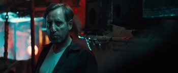 Movie still from “Black Sea” (2014), directed by Kevin Macdonald – A man standing in a dark room next to lights; Close Up shot, Low angle