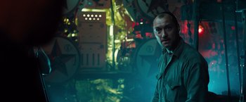 Movie still from “Black Sea” (2014), directed by Kevin Macdonald – A man standing next to a ship in a room filled with lights; Medium shot, Low angle