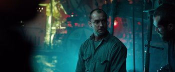Movie still from “Black Sea” (2014), directed by Kevin Macdonald – A man standing in a dark room with lights in the background; Medium shot, Low angle