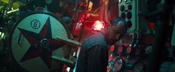 Movie still from “Black Sea” (2014), directed by Kevin Macdonald – A man standing in front of a bunch of clocks; Medium shot, Low angle